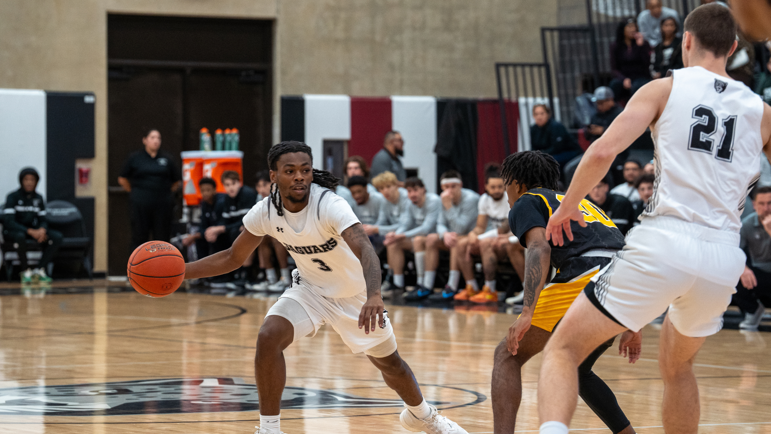 Basketball player with jersey number 3 dribbling the ball past defenders.