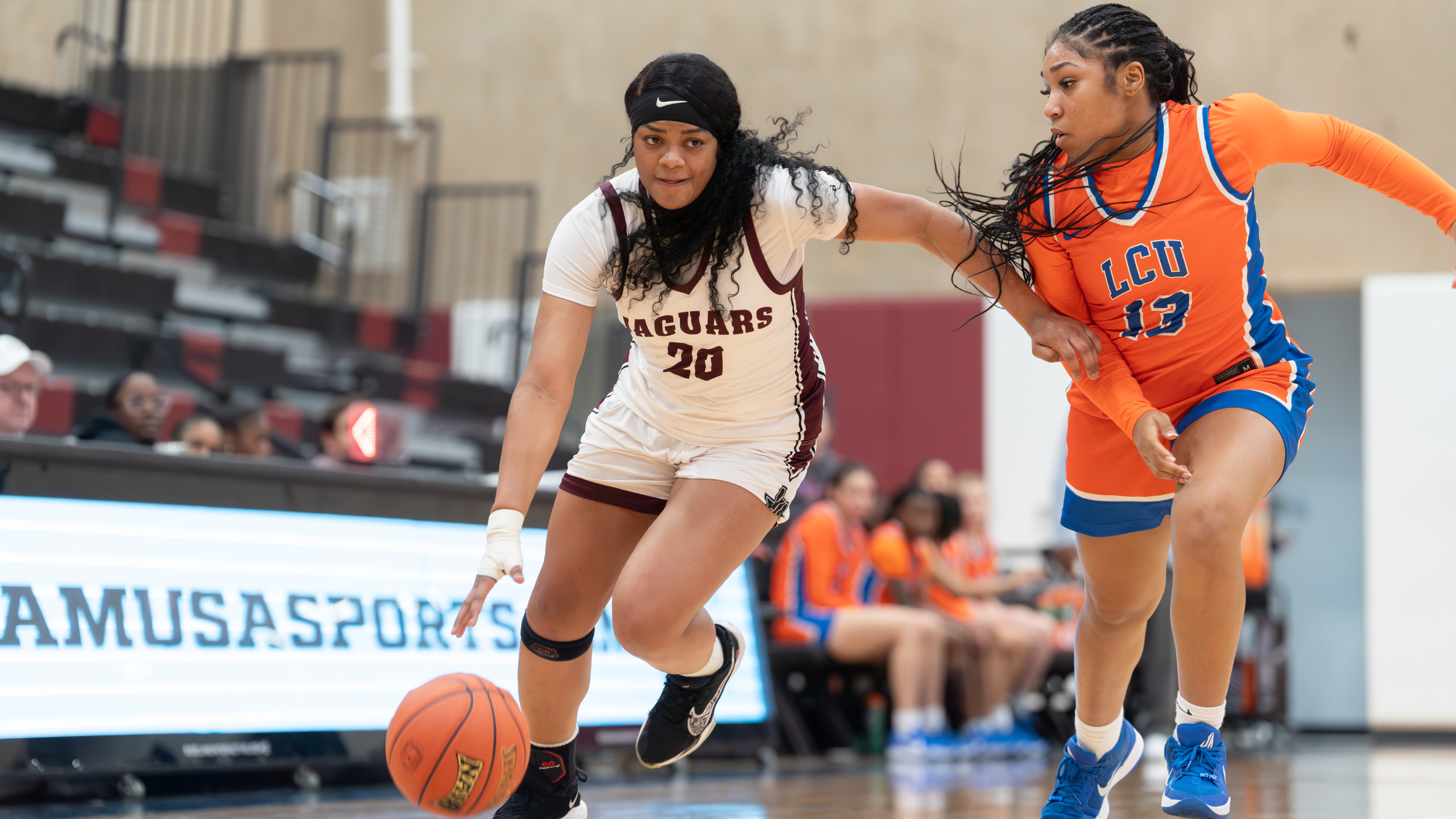 Jaguar Basketball player with jersey number 20 dribbling past defender from LCU.